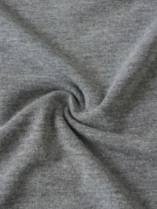 Detailed close-up shot of soft grey cotton knit fabric texture with natural twists. Material view.