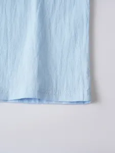 Close-up detail of light blue casual shirt hem, showcasing fine fabric texture and neat stitching.