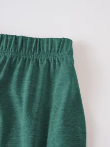 Dark green elastic waistband detail shot, soft and comfortable casual apparel fabric texture.