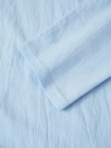 Detailed close-up view of light blue men's long sleeve casual shirt cuff fabric texture.