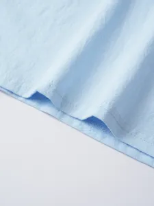 Close-up of light blue men's casual shirt fabric, showing fine texture and stitching.