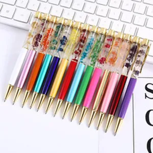 Macro view of colorful metal ballpoint pens featuring delicate dried flowers in clear barrels