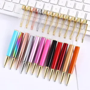 Variety of colorful metal ballpoint pens with clear crystal tops on a white desk.