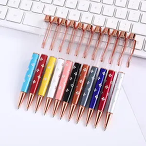 Colorful metal ballpoint pens with rose gold accents arranged on a white keyboard.