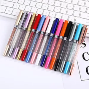 Detailed view of colorful crystal-filled metal ballpoint pens arranged on a white desk.