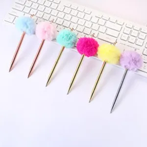 Creative metallic ballpoint pens with colorful fluffy pom-pom tops on white keyboard