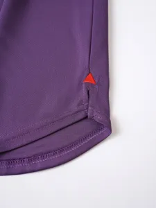 Purple athletic apparel hem detail with red embroidered triangle accent, breathable fabric.