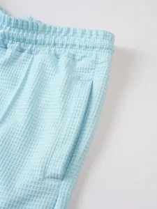 Light blue waffle knit fabric detail of men shorts featuring elastic drawstring waistband and pocket.