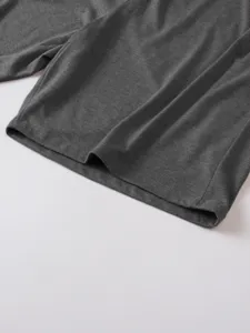 Detailed close view of a dark gray men's short sleeve knit polo shirt hem with clean stitching.