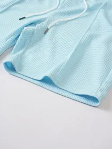 Close-up detail of light blue waffle knit shorts with white drawstring for men's summer wear.