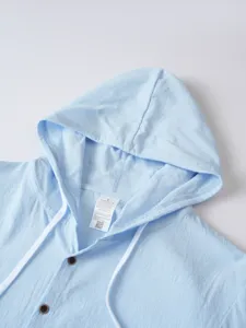 Gros plan sur les détails du sweat à capuche bleu clair avec cordons et boutons.