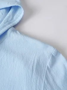 Gros plan détail de l'épaule et de la capuche de la chemise à capuche en lin et coton.