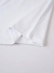 Close-up detail of white short sleeve t-shirt hem, showing neat stitching and soft fabric texture.