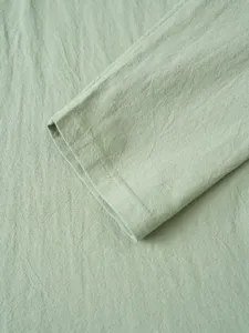 Close-up of sage green shirt cuff, highlighting fine fabric texture and neat stitching details.