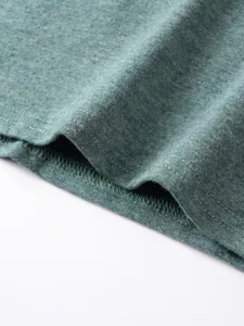 Close-up of green t-shirt fabric hem and stitching detail for men casual summer wear.