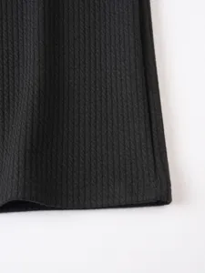 Close-up detail of black knitted vertical striped fabric, showing fine texture and neat hem.