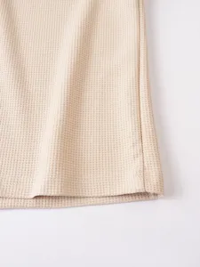 Close-up detail of casual waffle knit fabric hem, showing texture and neat stitching.