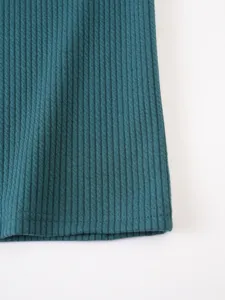 Close-up detail of dark teal ribbed knit fabric showing fine vertical texture and hem stitching.