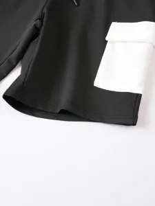 Primo piano dettagliato di pantaloncini cargo neri da uomo con tasca bianca e coulisse.