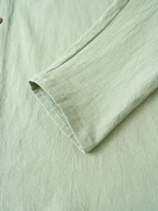Gros plan détail d'une manchette de chemise en lin vert clair avec texture de couture.