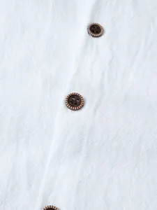 Détail de tissu de chemise en coton lin blanc avec de beaux boutons à motifs bruns