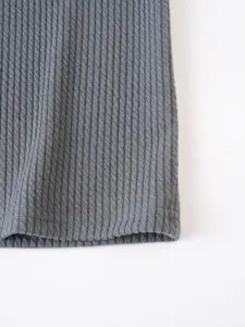 Close-up detail of mens grey ribbed knit tank top fabric, showing vertical texture and hem.