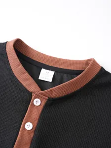 Close up view of mens waffle knit henley shirt collar with contrast color trim and buttons.