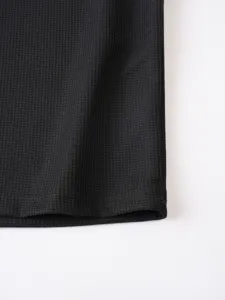 Black waffle knit fabric detail, soft textured material macro close up shot showing fine texture.