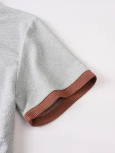 Close-up detail shot of the grey waffle knit short sleeve featuring a contrast brown cuff.