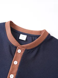 Detailed view of mens waffle knit henley short sleeve shirt collar with contrast buttons.