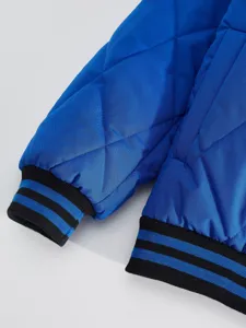Close-up view of royal blue quilted jacket sleeve with black and blue striped ribbed cuffs.