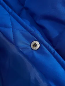 Close-up detail of winter men jacket quilted fabric and metallic snap button design.