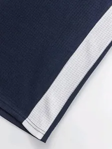 Men's casual polo shirt fabric detail close-up, navy blue body with white contrast side stripe.