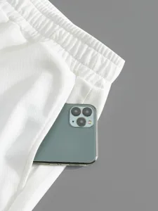 Vue detaillee de la poche d'un short blanc avec telephone, tissu texture, fond propre.