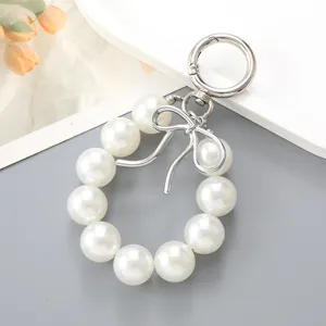 Elegant white pearl wristlet keychain featuring a silver metal bow charm for bag accessory