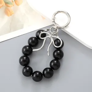 Black bead keychain with silver bow charm and circular clasp bag accessory