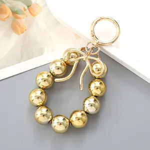 Fashionable gold metallic bead bag charm with bow detail and circular clip