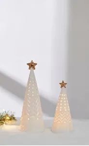 Close-up of elegant white ceramic glowing Christmas trees featuring gold star toppers.