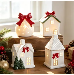 Four glowing white ceramic Christmas house ornaments with red bows on a rustic wooden table