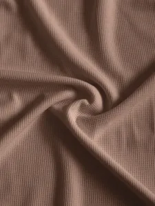 Vue rapprochée détaillée d'un tissu en maille gaufrée marron doux, montrant une texture fine.
