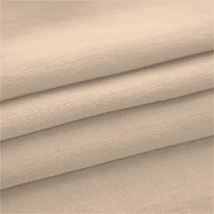 Detailed close-up view of soft beige fabric texture with neat folds for garment production.