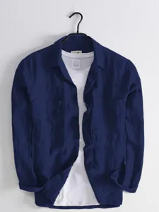 Detailed view of men's dark blue utility long sleeve shirt with double pockets layered on white tee.