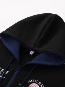 Men's black zip hoodie detail, hood with blue lining and chest print close-up view.