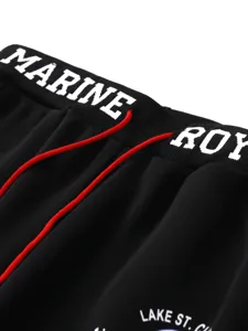 Detailed view of black pants elastic waistband with bold white printed text and red drawstrings.