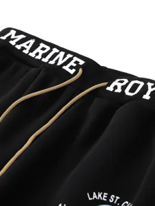 Close-up detail of men's casual black sweatpants featuring white waistband text and drawstrings.