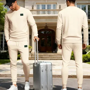 Ensemble sweat-shirt et pantalon de survêtement beige présenté devant une belle villa.