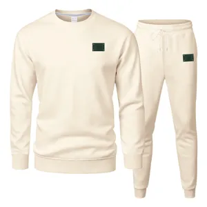 Vue détaillée de l'ensemble sweat-shirt et pantalon de survêtement beige avec un patch logo vert.