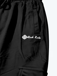 Close-up detail of black men's cargo pants with side pocket and white embroidery logo.