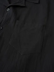 Detalle de camisa de lino negro de manga larga, mostrando cuello, boton y bolsillo.