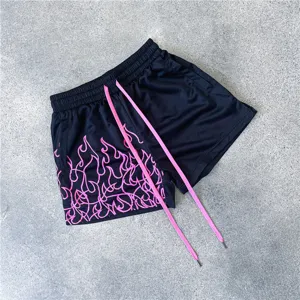 Nahaufnahme von schwarzen Mesh Sportshorts mit pinkem Flammenmuster und langen Kordeln.